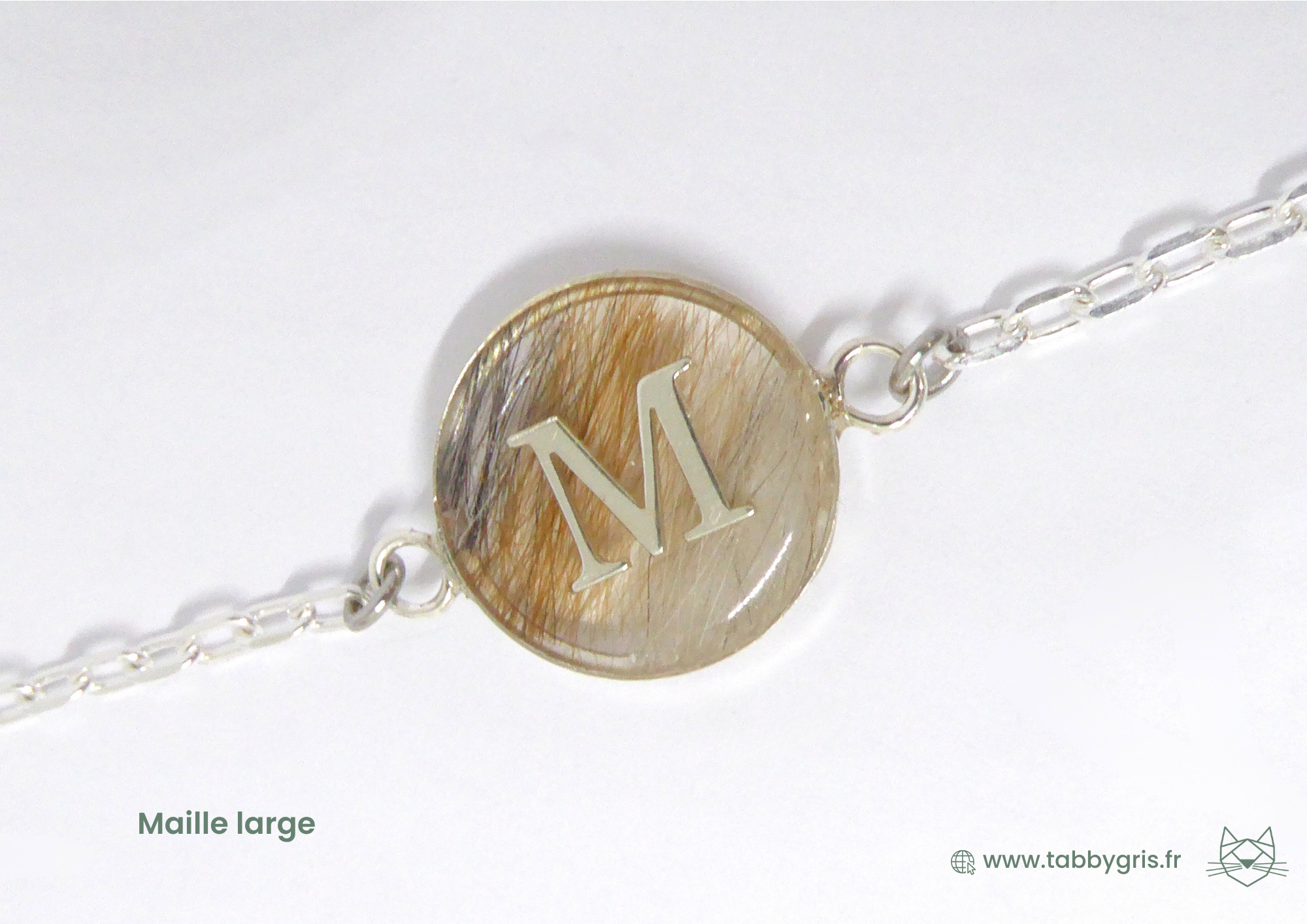 Bijou souvenir mèche de cheveux contenant les mèches de 3 frères et une initiale "M" en son milieu pour la symbolique de la maman. Offert à leur mère par ses 3 enfants.