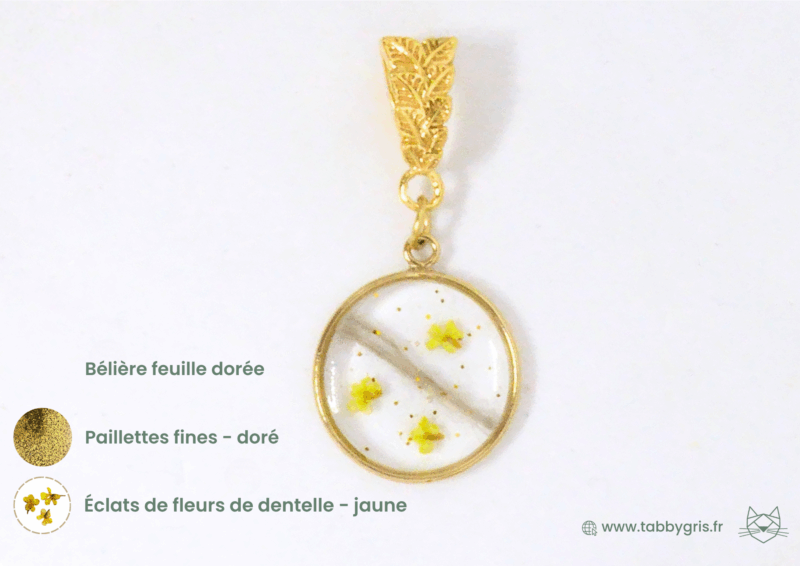 Bijou en or mèche cheveux avec quelques paillettes fines dorées, des éclats de fleurs de dentelle jaune et une bélière feuille dorée. Créez votre bijou unique chez Tabby Gris, artisan créateur de bijoux