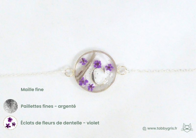 Bijou en crins de cheval contenant les crins de deux chevaux, des fleurs violettes et une lettre initiale C. Sur ce modèle, nous ajoutons une maille fine en argent 925 pour porter élégamment ce bracelet