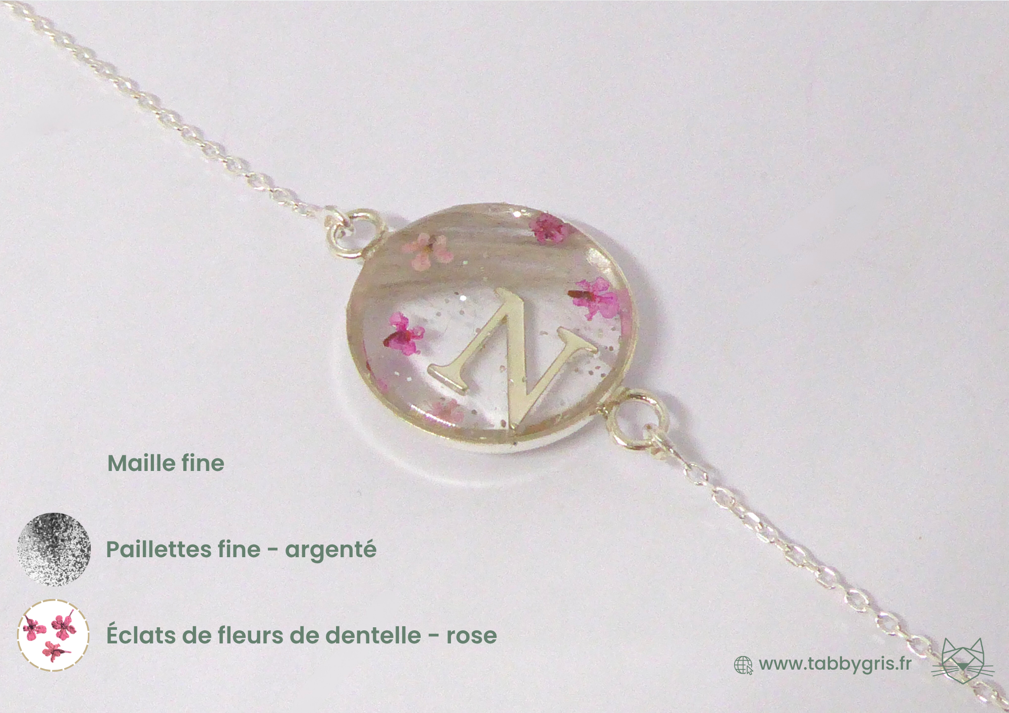 Bijou en crins de cheval avec une initiale P au milieu, deux mèches de crins de chaque côté et des éclats de fleurs de dentelle rose.