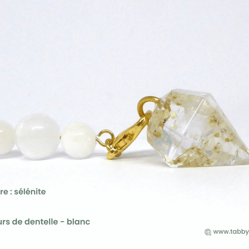 Pendule divinatoire améthyste incluant ici une perre sélénite et des fleurs de dentelle en blanc. Vous avez un large choix de pierre et d'agréments à glisser dans la résine et sur la chaîne pour avoir un pendule personnalisé et chargé qui vou permette de créer une connexion forte